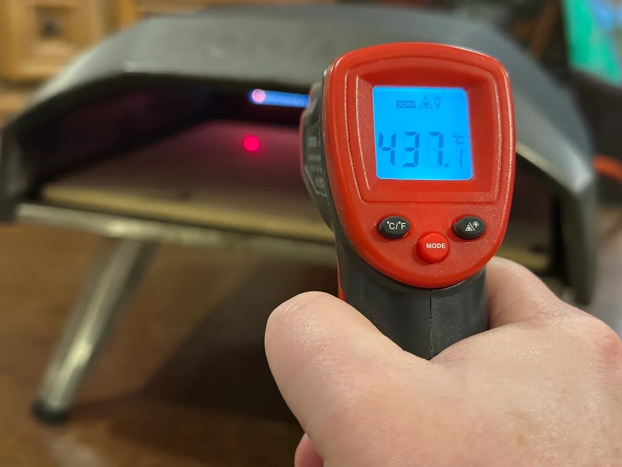 Thermomètre infrarouge pointé vers la pierre de cuisson de l'Ooni Koda 12 affichant 430°C — la température minimale avant d'enfourner