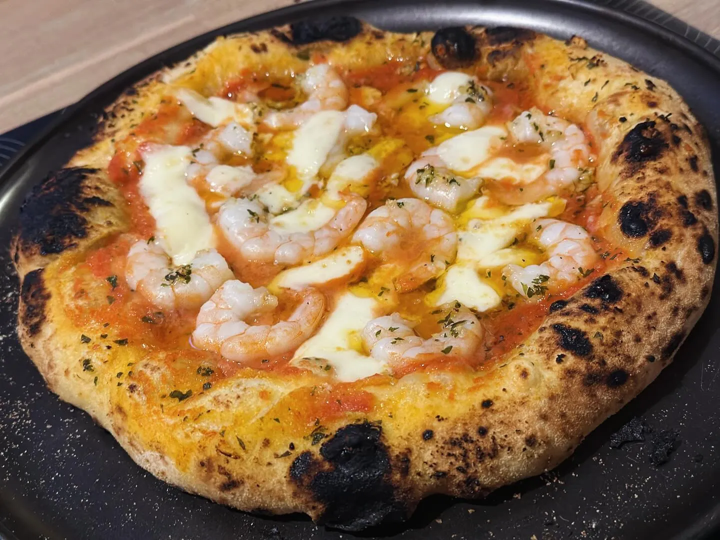 Pizza sur la pelle à pizza à l'entrée du four Ooni Koda 12, prête à être enfournée — flamme bleue visible en arrière-plan